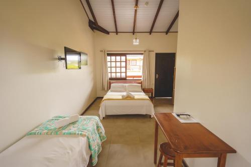 um quarto com duas camas e uma mesa em Pousada Village Garopaba em Garopaba