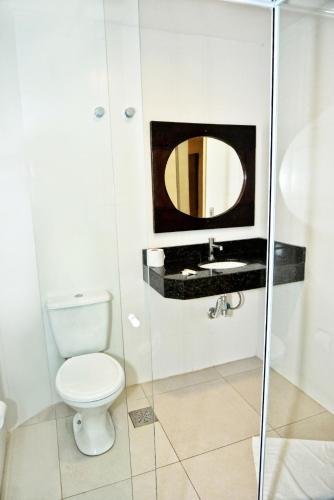 a bathroom with a toilet and a mirror at De Rose Centro Hotel in Torres