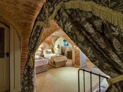 a bedroom with two beds and a brick wall at Yew Tree Nook in Ashbourne