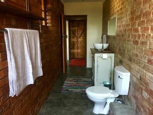 La salle de bains est pourvue de toilettes blanches et d'un lavabo. dans l'établissement Kingfisher Cottage, à Umkomaas