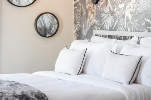 a white bedroom with white pillows and a mirror at Le Dortoir Boutique Suites in Nice