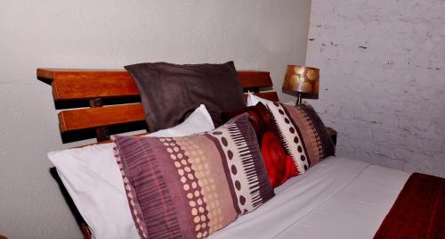 a bed with a bunch of pillows on it at Gately Inn Entebbe in Entebbe