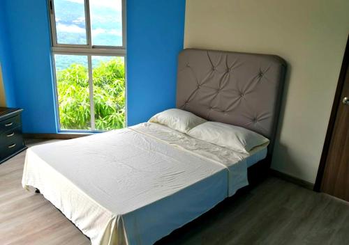 een bed in een blauwe kamer met een groot raam bij Casa Quinta Campestre con Piscina Privada Anapoima in Anapoima