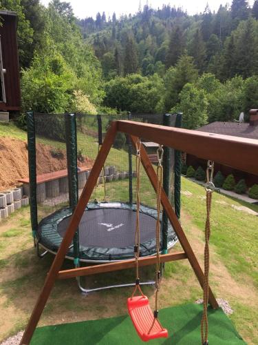 a swing set with a trampoline in a yard at Drevenice Oščadnica in Oščadnica