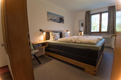 Schlafzimmer mit einem Bett, einem Schreibtisch und einem Fenster in der Unterkunft Haus Glasella in Schruns-Tschagguns