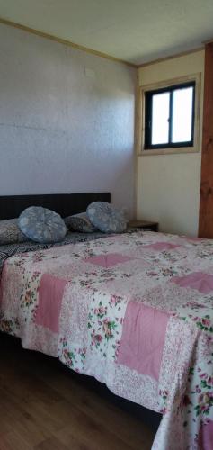 1 dormitorio con 1 cama con manta rosa y blanca en Domos y habitación independiente Eva-Ray, en Panguipulli