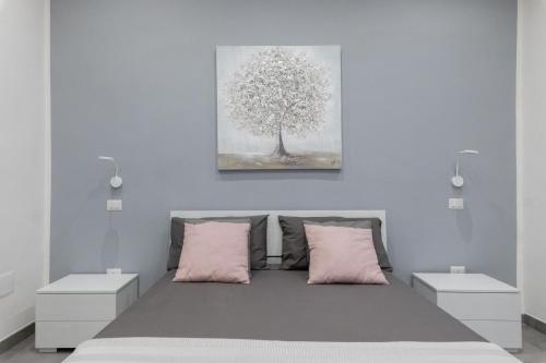 ein Schlafzimmer mit einem Bett mit rosa Kissen und einem Baum in der Unterkunft Dante Square in Neapel
