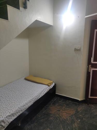 a small bed in a room with a light on the wall at jayaram Home in Chittoor