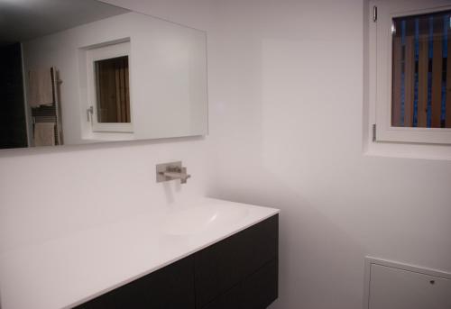 eine weiße Küche mit einem Waschbecken und einem Spiegel in der Unterkunft Corte delle Camelie in Vira
