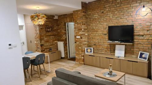 a living room with a brick wall and a tv at Sopot Special Apartments in Sopot