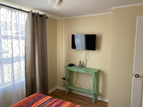 a room with a television on a wall with a table at Departamento - Place - king Home - Factura - Central - Empresas - Parking - Wifi in Chillán