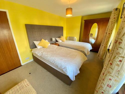 Kilbroney Rest في روستريفور: سريرين في غرفة بجدران صفراء