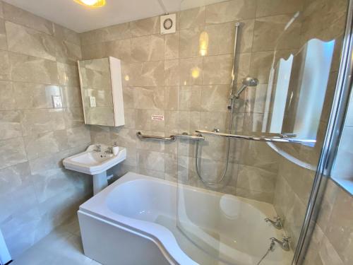 ein Badezimmer mit einer Dusche, einer Badewanne und einem Waschbecken in der Unterkunft Kilbroney Rest in Rostrevor