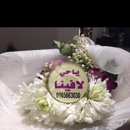 a sign on a bouquet of flowers on a bed at لافينا حائل للاجنحة الفندقية in Hail