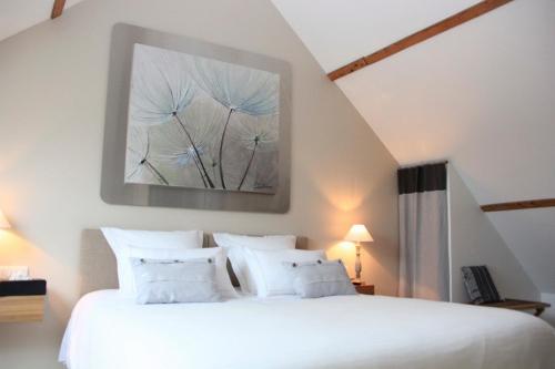 a bedroom with a white bed and a painting on the wall at Au Coeur Des Hôtes in Steenvoorde