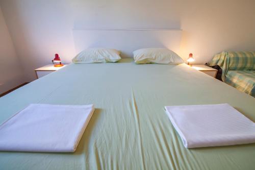 a large white bed with two white pillows on it at Apartments Radić in Bol