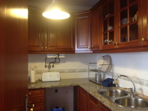 a kitchen with wooden cabinets and a sink at Casa do Baleal in Baleal