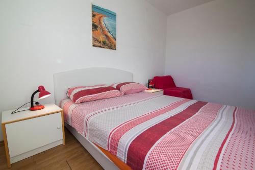 a bedroom with a bed and a red chair at Apartments Radić in Bol