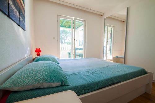 a bedroom with a bed with green sheets and a mirror at Apartments Radić in Bol