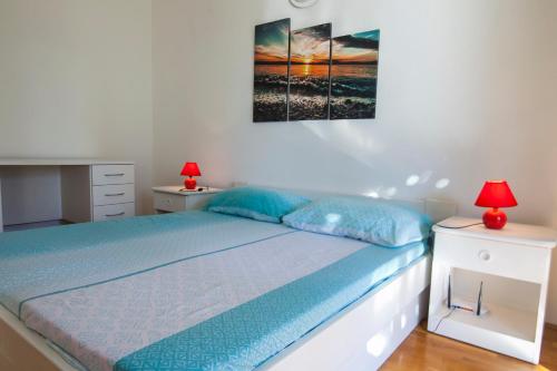 a bedroom with a bed with blue sheets and two lamps at Apartments Radić in Bol