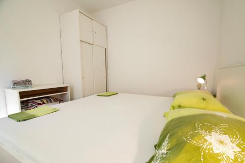 a white bedroom with a bed and a cabinet at Apartments Radić in Bol