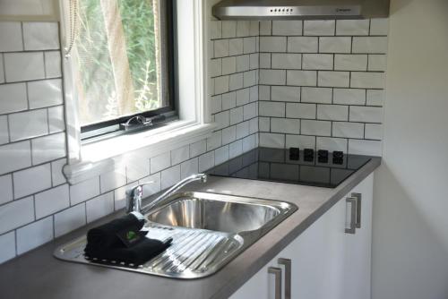 a kitchen sink with a hair dryer sitting next to a window at Great Ocean Road Cottages in Lorne