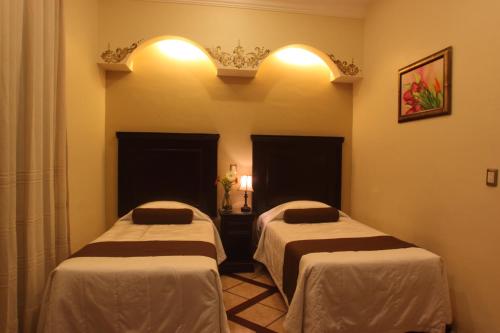 
a hotel room with two beds and two lamps at Hotel CasAntica in Oaxaca City
