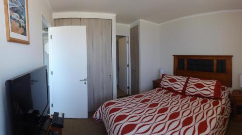a bedroom with a red and white bed and a tv at Departamentos Parque Costanera in Antofagasta