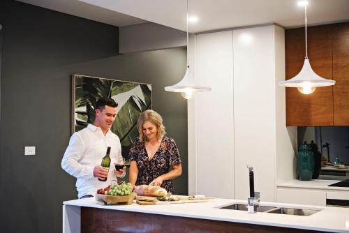 a man and woman standing in a kitchen with a bottle of wine at Kirsten Accommodation Mudgee in Mudgee