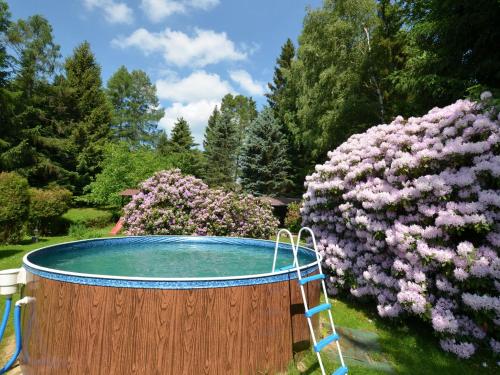 uma banheira de hidromassagem num jardim com flores cor-de-rosa em Holiday home in Star K e any with fenced garden em Staré Křečany