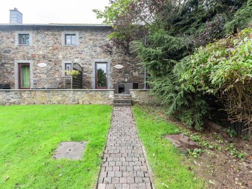 a stone house with a brick path in front of it at Charming Cottage in Stoumont with colourful garden in Exbomont