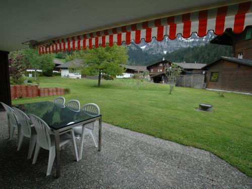 una mesa y sillas en un patio con patio en apartment in Lenk in Simmental Bernese Oberland en Lenk