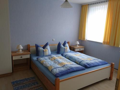 a bedroom with a bed with blue sheets and a window at Pretty Apartment in Wiek with Garden in Wiek auf Rügen 