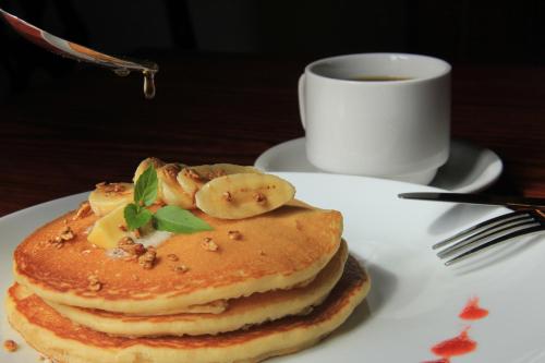 a stack of pancakes with bananas and a cup of coffee at La Casa del Marqués in Comitán de Domínguez