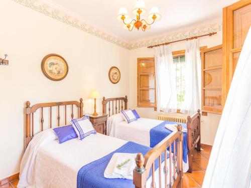 a bedroom with two beds and a chandelier at Villa in Priego with pool near Sierras Subbéticas in Priego de Córdoba
