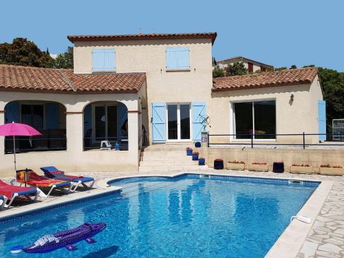 a house with a swimming pool with chairs and a house at Stylish villa with private pool in Félines-Minervois