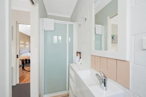 a white bathroom with a sink and a mirror at Motel Marengo in Apollo Bay