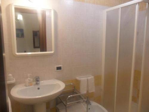 a bathroom with a sink and a toilet and a mirror at Hotel Antica Cascina Del Golfo in Scopello