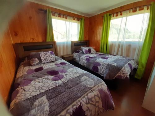 two beds in a bedroom with green curtains at Cabaña San Pedro in Malalcahuello