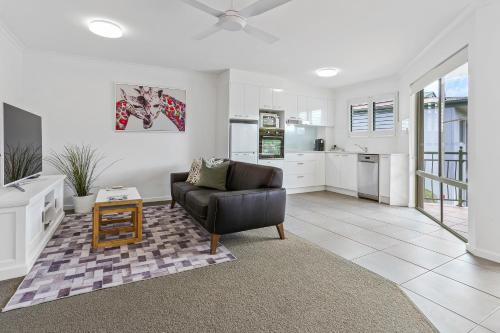 a living room with a couch and a kitchen at Noosa River Retreat Holiday Apartments in Noosaville