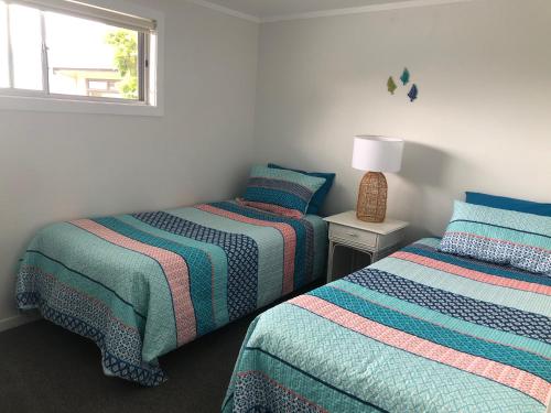 a bedroom with two beds and a window at Taurikura Bay Relax and Explore in Whangarei Heads