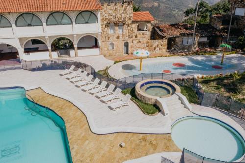 a resort with a pool with chairs and a water slide at Hotel El Castillo Chinauta in Chinauta