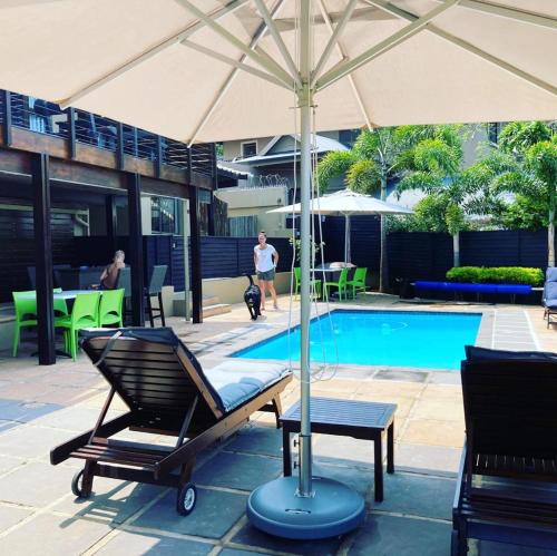 a pool with a chair and an umbrella next to a pool at Billfish Apartments in Ballito