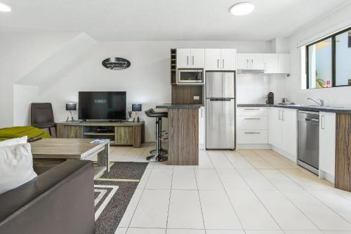 a living room with a kitchen with white cabinets at Noosa River Retreat Holiday Apartments in Noosaville