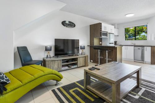 a living room with a yellow couch and a kitchen at Noosa River Retreat Apartments - Perfect for Couples & Business Travel in Noosaville
