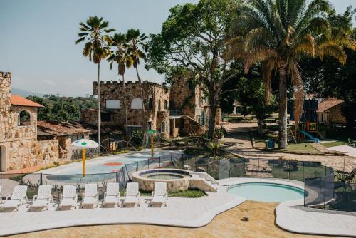 a resort with a pool and chairs and palm trees at Hotel El Castillo Chinauta in Chinauta