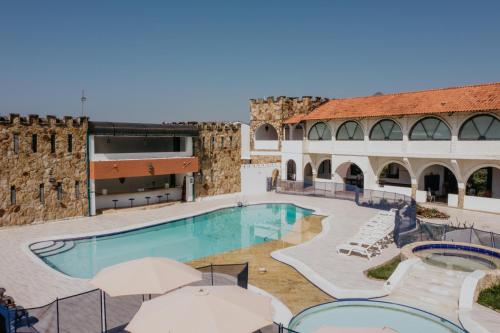 a large pool with chairs and umbrellas next to a building at Hotel El Castillo Chinauta in Chinauta