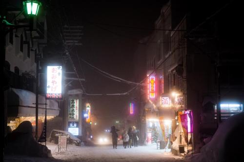 a group of people walking down a street at night at Kogakuro in Myoko