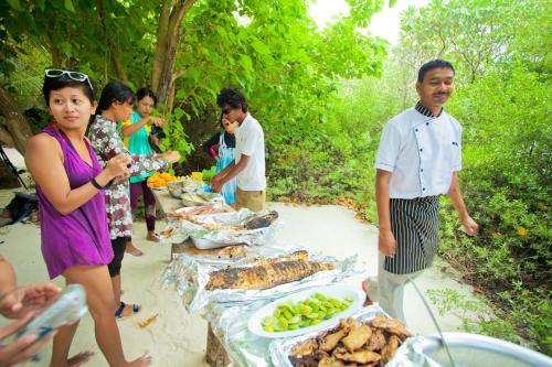 a group of people standing around a table with food at Kaani Village & Spa in Maafushi