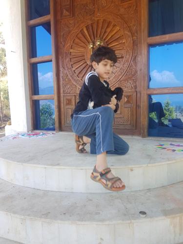 a young boy sitting in front of a door at Jandyal Farm House in Malshej Ghat